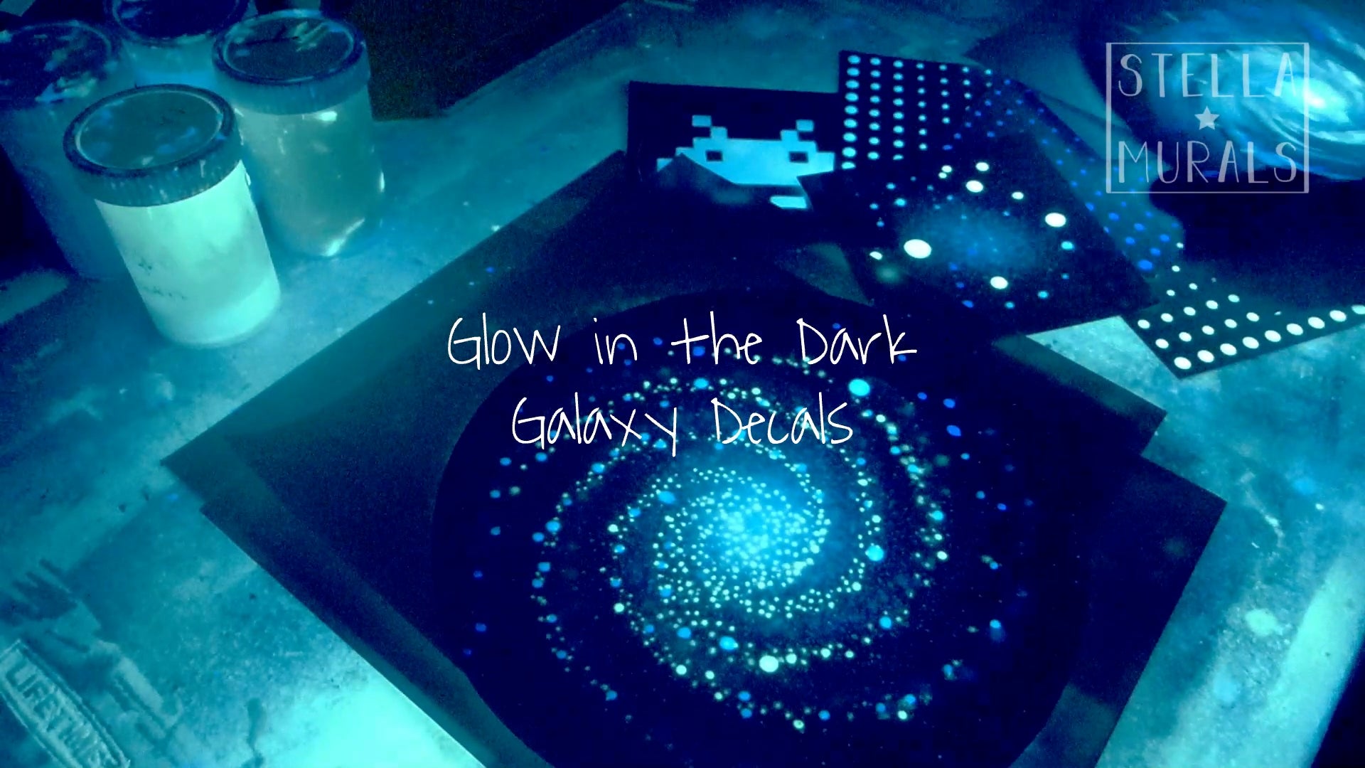 glow in the dark galaxy decals glowing in the dark on a workbench in a art studio. Also with glow in the dark stars and little space invader sticker.