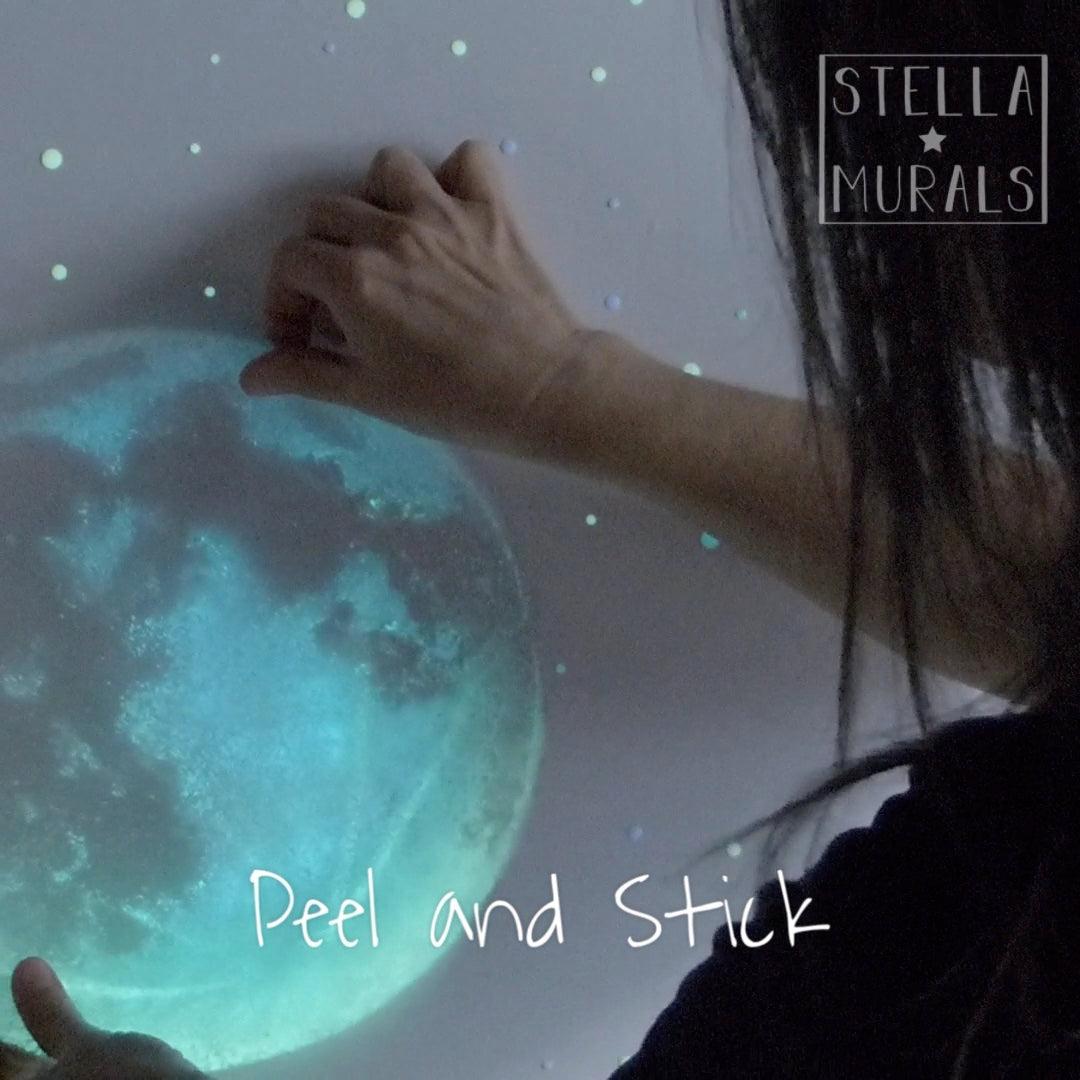 clear glow in the dark decals of luminescent moon and stars installing them onto a wall.