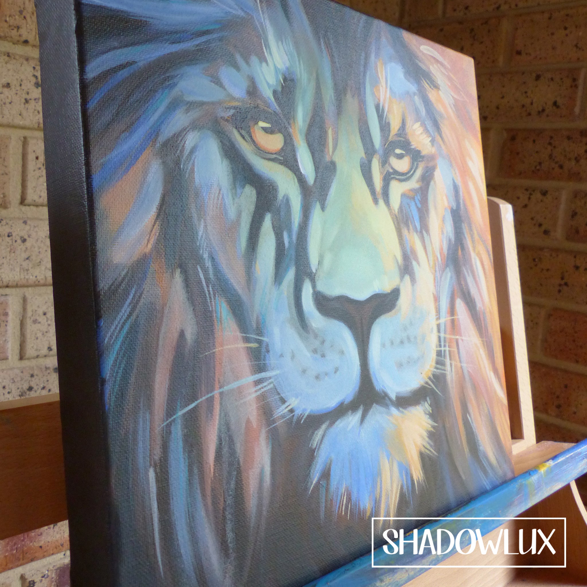 Painting of a lion’s face in warm daylight tones displayed on an easel