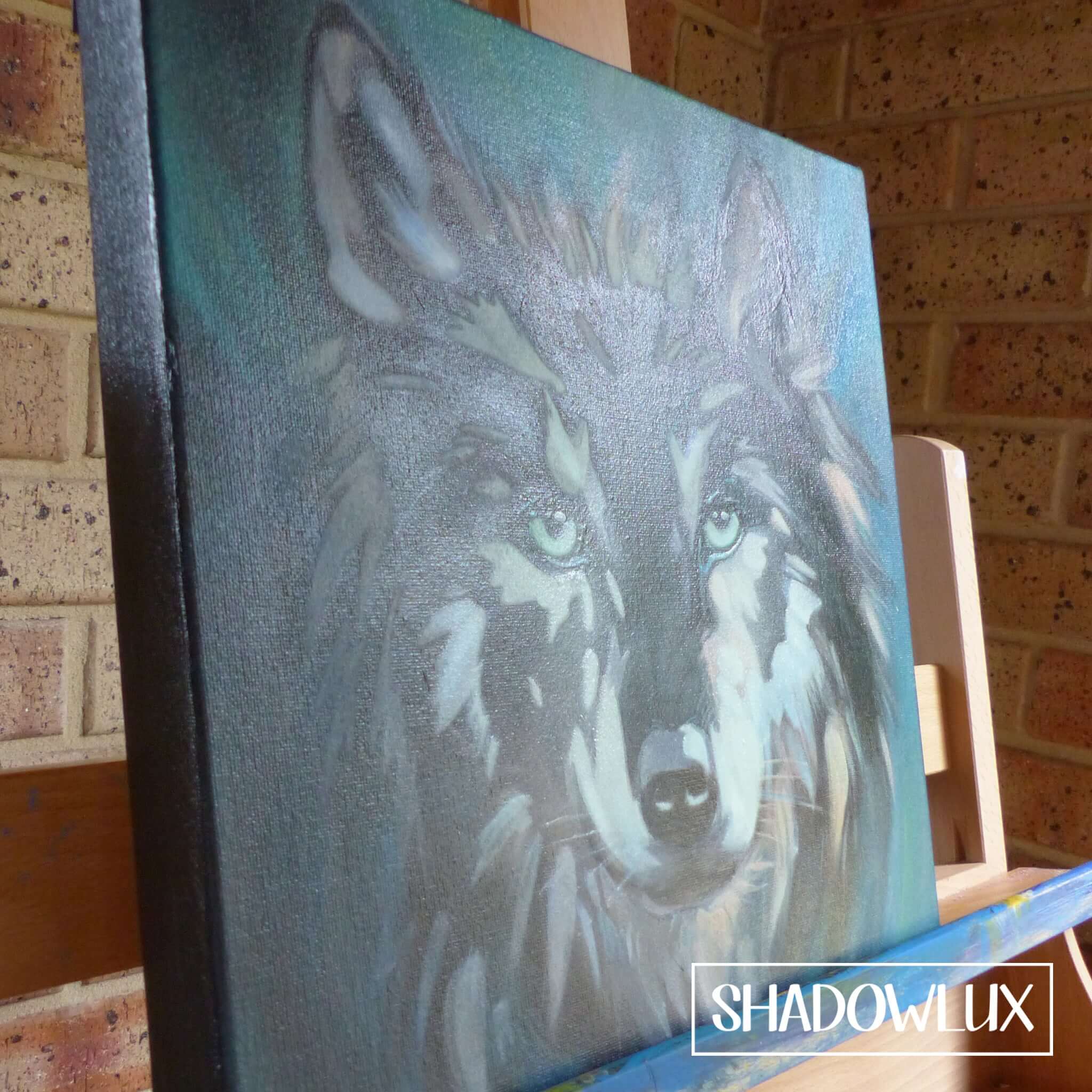 glow in the dark deep edge canvas artwork of a wolf head sitting on easel