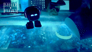 Emo desk top Ai robot on my glow in the dark art workbench in studio. Robot is dancing while I and packing up some glow in the dark star stickers