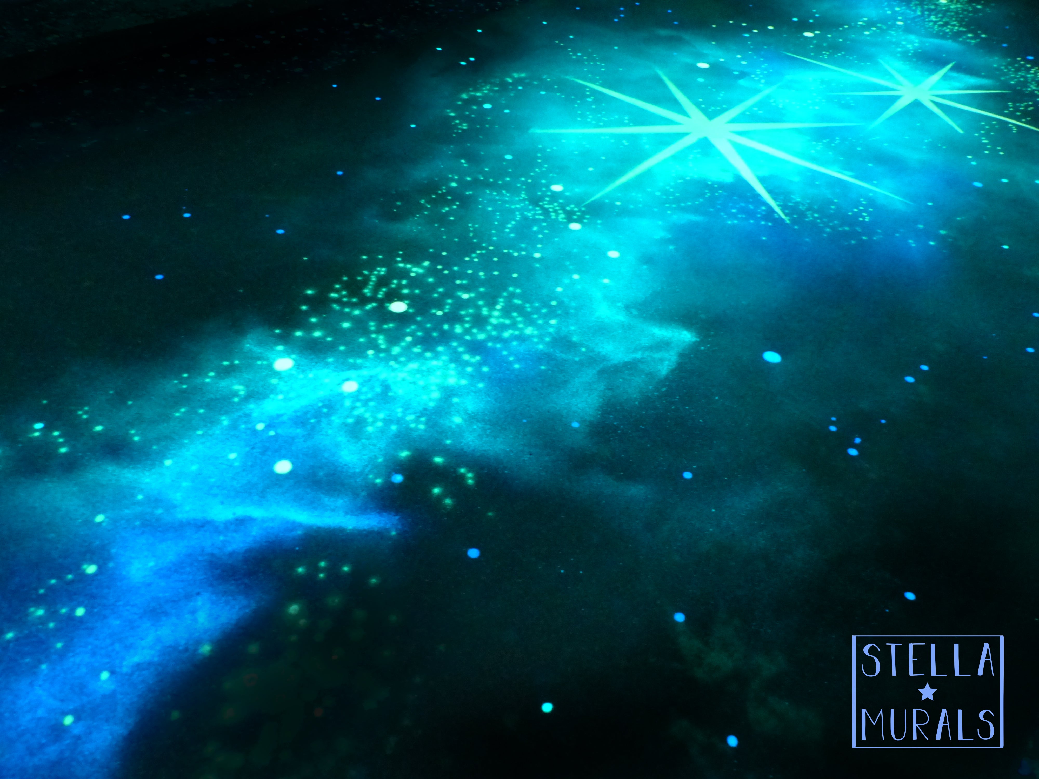 Glow in the dark nebula painted with stars in aqua and blue colours on a peel and stick decal for walls.