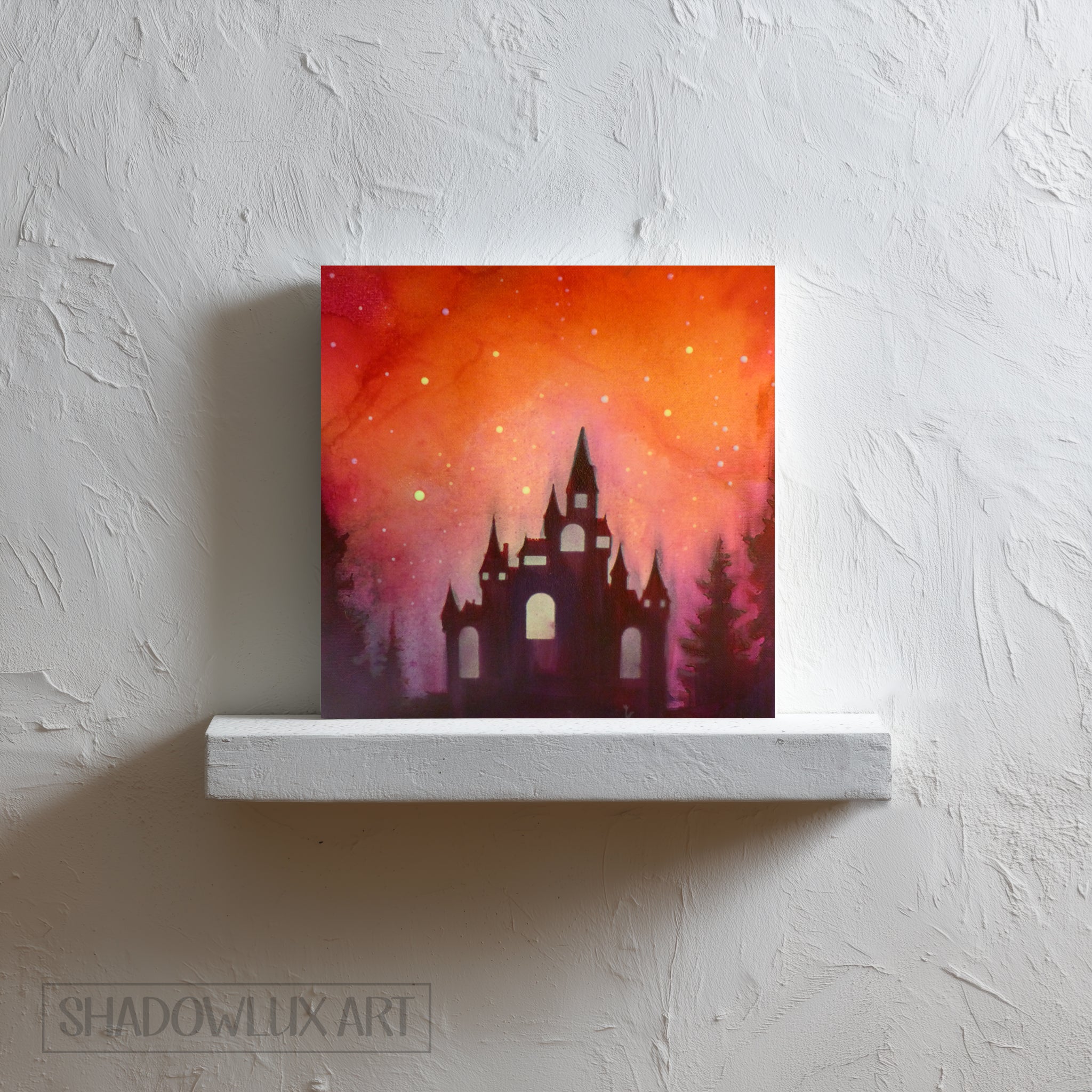 Artistic depiction of a glow in the dark castle silhouette against a vibrant orange and pink sky on a white shelf.
